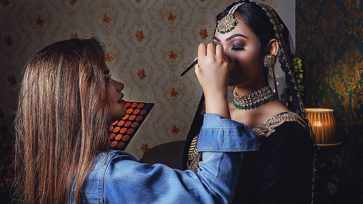 A diverse group of students practicing airbrush foundation application under instructor supervision during accredited makeup artist courses
